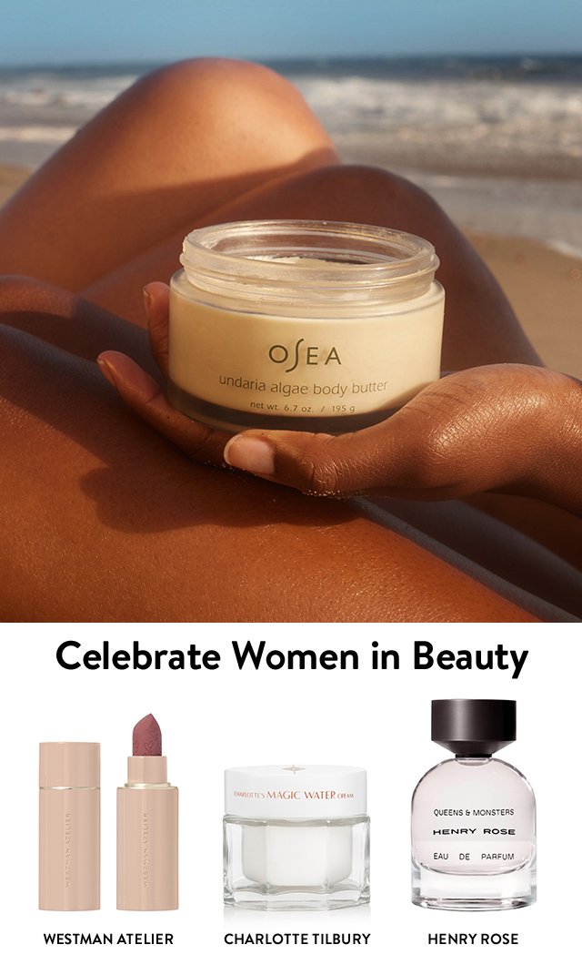 A hand holding a jar of OSEA body butter. Westman Atelier lipstick, Charlotte Tilbury moisturizer and Henry Rose perfume.