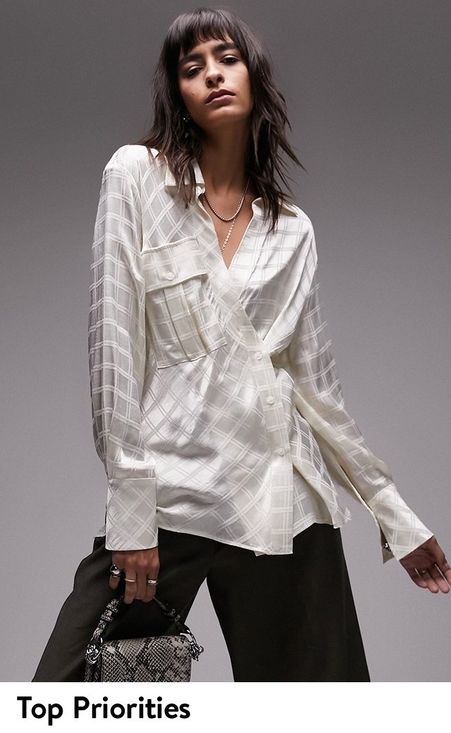 A woman wearing an asymmetric button-up shirt with black pants.