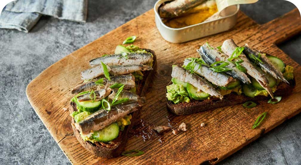 Toast with anchovies and cucumbers on it. 