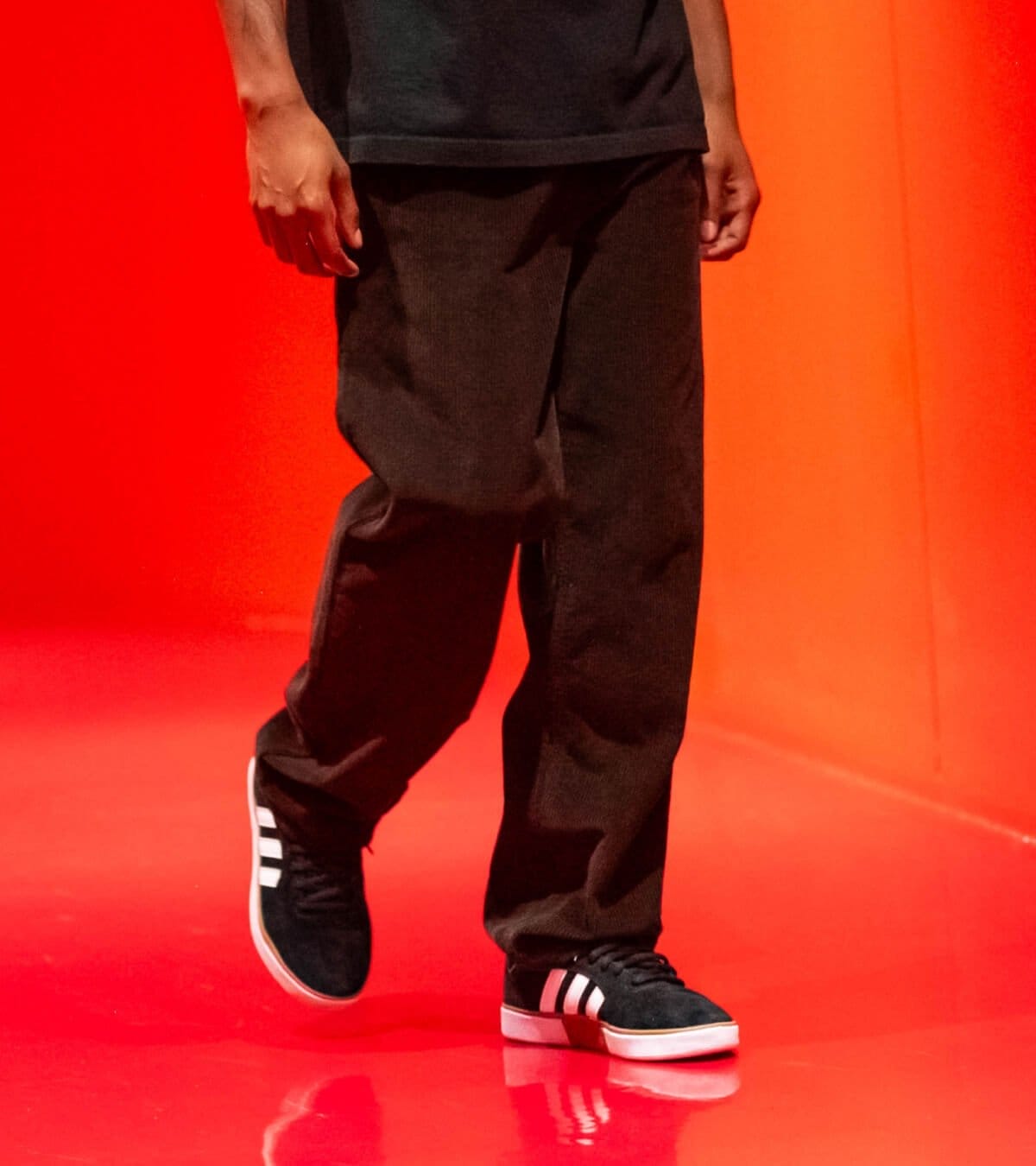 Man wearing brown corduroy Empyre branded pants in an all red room