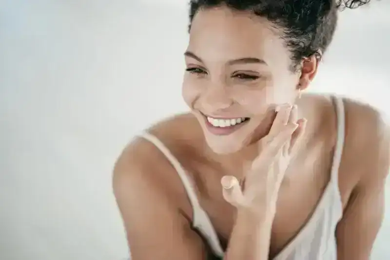 Smiling model in camisole applied face cream