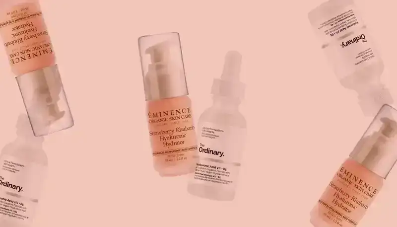 Best Hyaluronic Acid Serums 2024: Bottles of skin-care serums from The Ordinary and Eminence on a light pink background.
