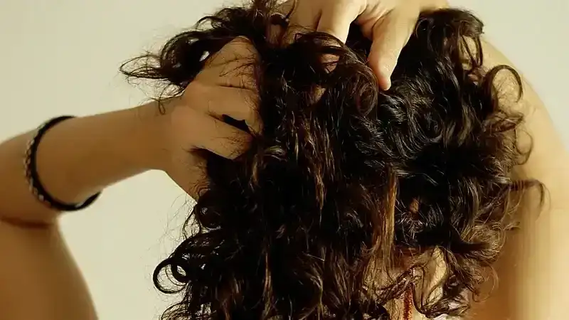 Person holding curly hair from back