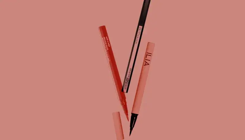 Different eyeliners from Maybelline New York, Ilia, and Wet n' Wild on a red background