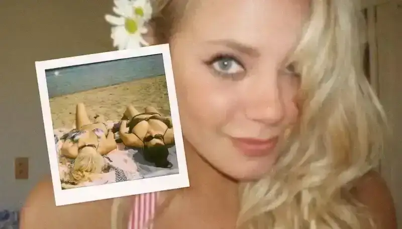 A girl takes a selfie with blonde hair and daisies behind her ear.