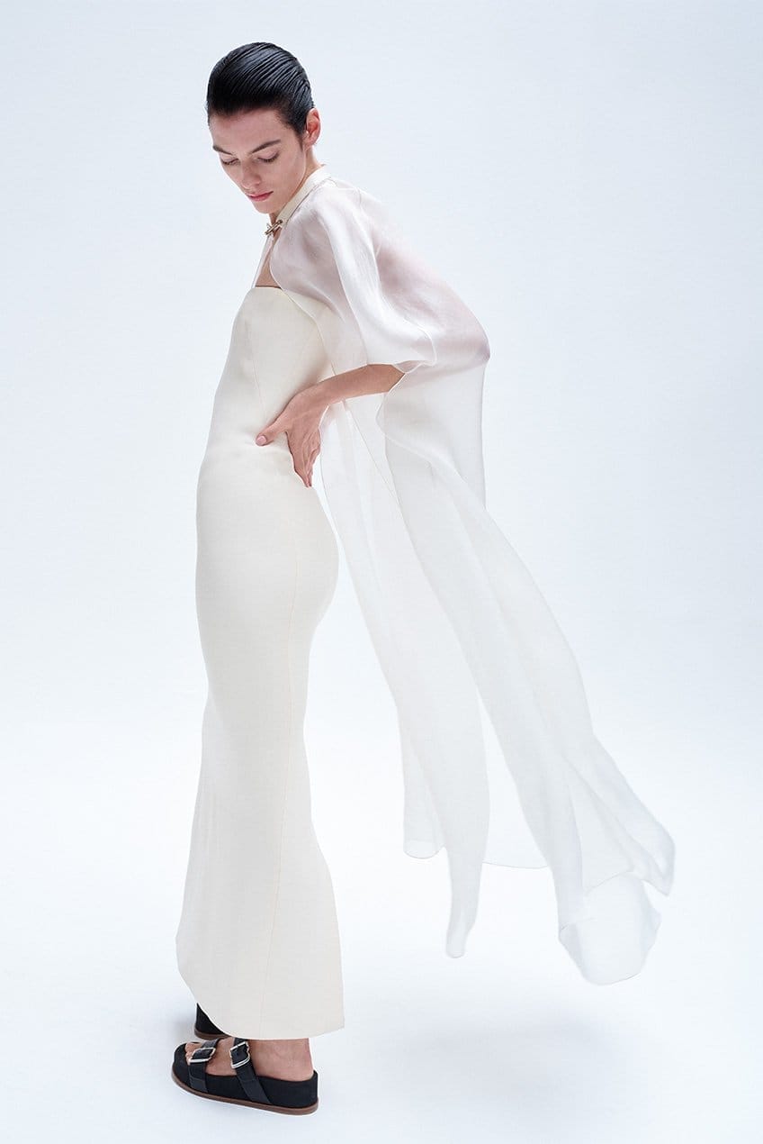 Model wears Gabriela Hearst - Opus Strapless Wool Crepe Maxi Dress and Rowena Silk Cape with Chain Detail