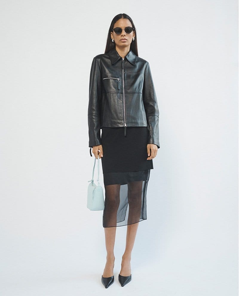 Model wears Saint Laurent - Logo Metal Oval Sunglasses, Proenza Schouler White Label - Annabel Zip-Front Leather Jacket, and The Row - Cybil Leather Mule Pumps