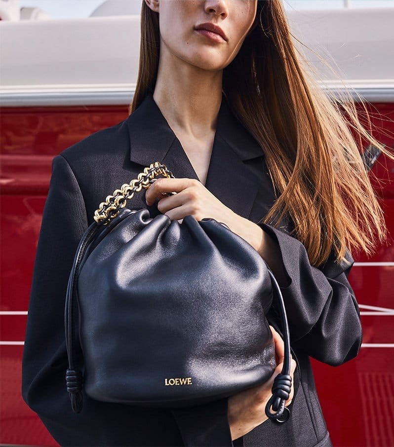 Model holds Loewe - x Paula’s Ibiza Flamenco Bucket Bag in Napa Leather with Chain in black