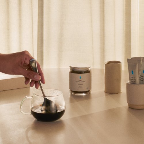 Image of hand stirring Craft Instant Espresso in glass mug.