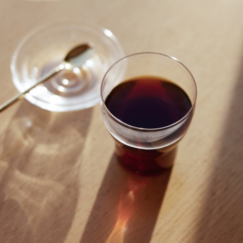 Image of cup of coffee in glass on wood table.