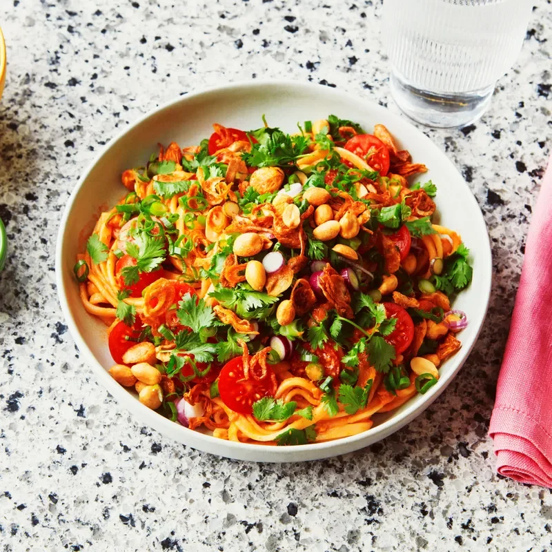 Chilled Tomato-Peanut Noodle Salad in a white bowl on black and white marble surface