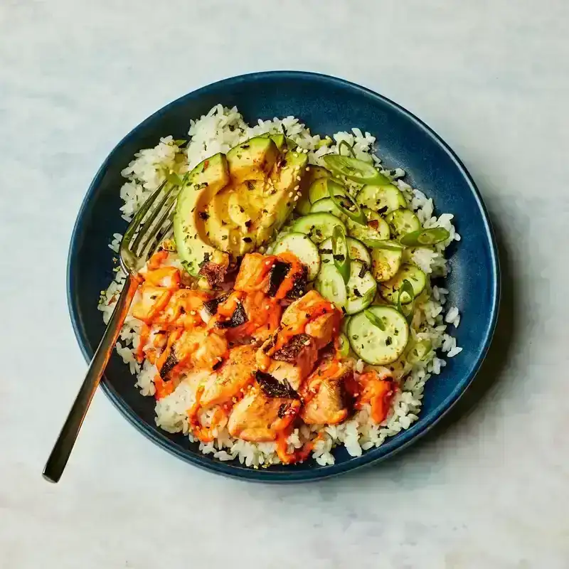 A blue bowl with salmon, rice, and avocado