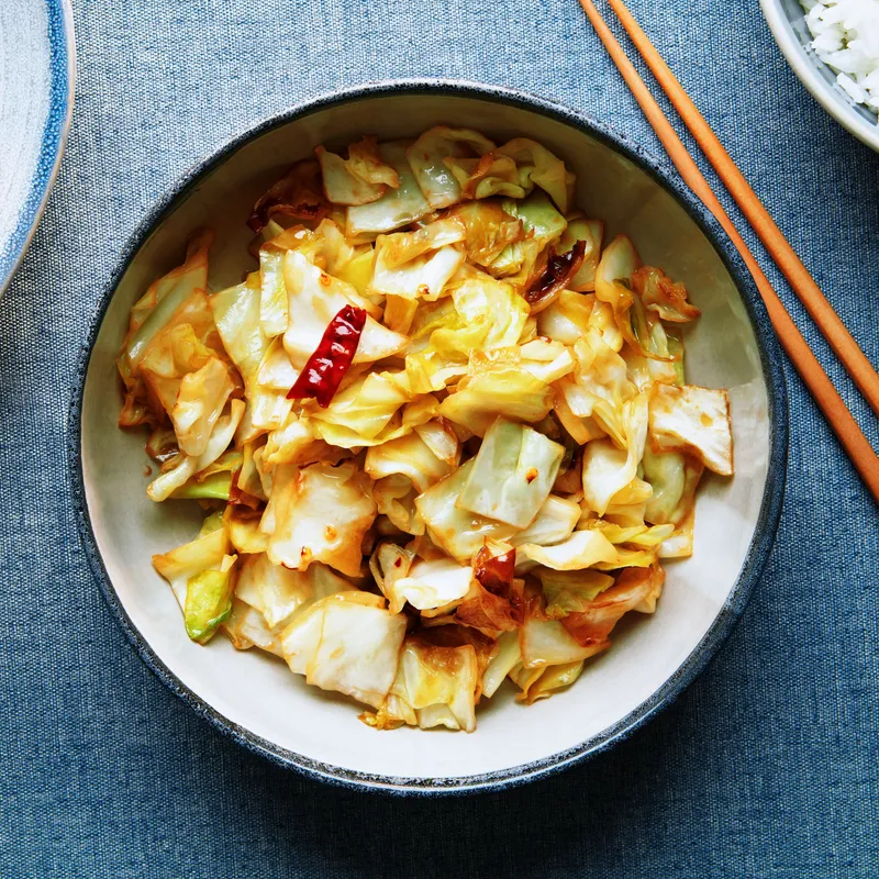 cabbage stir-fry in a white bowl on a blue fabric surface