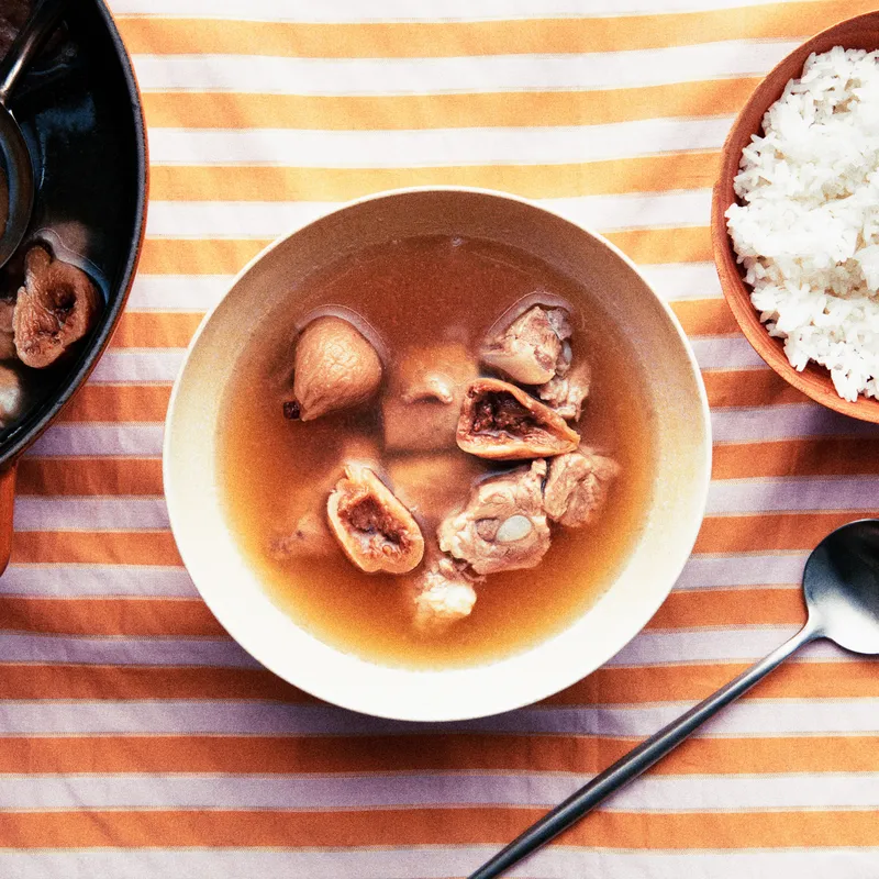 A bowl of pork rib soup with figs and a side of white rice.