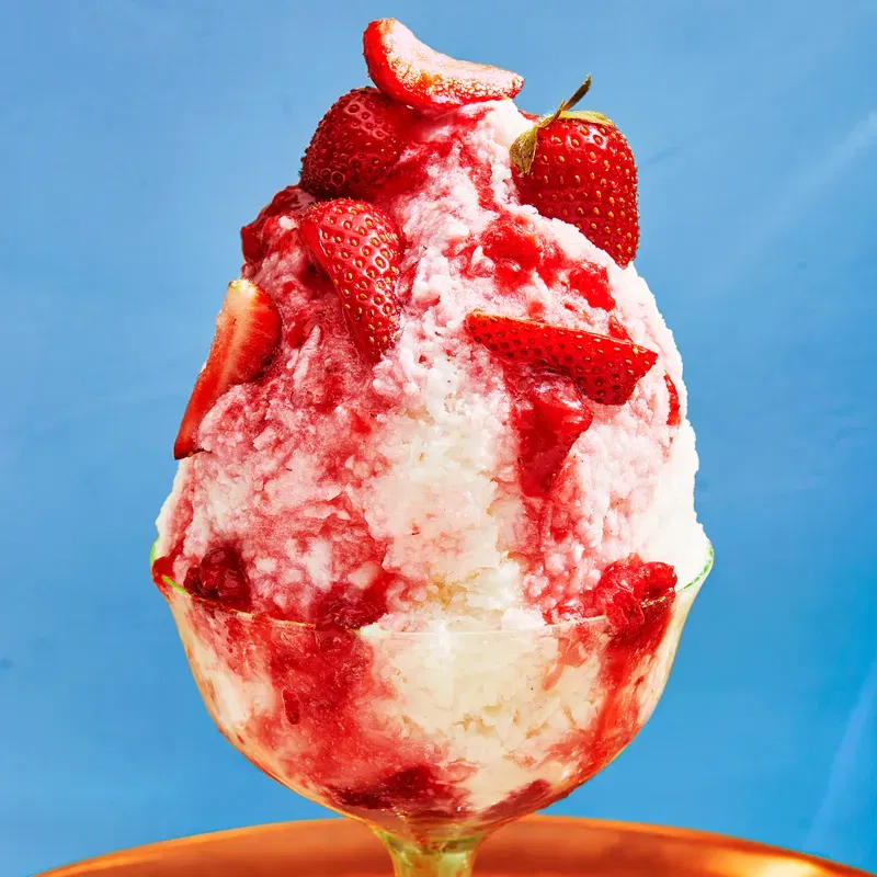 a cup of shaved milk with strawberries on a blue background