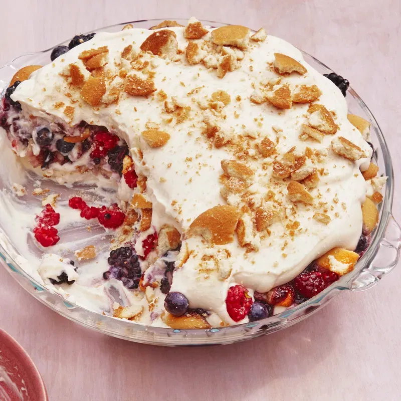 bowl of berry pudding with a basket of berries on the corner