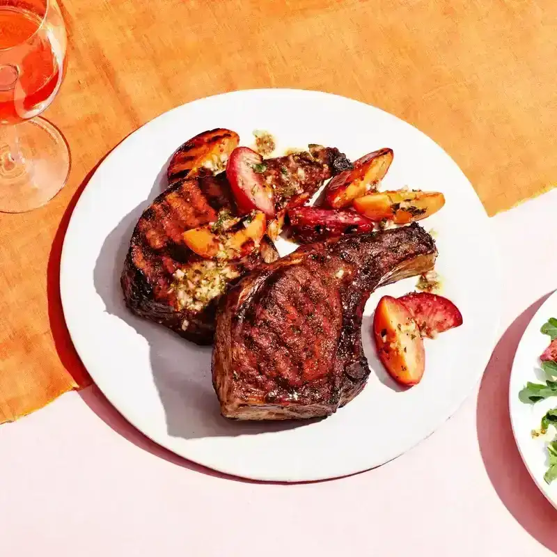 porkchops on orange linen and pink surface with salad on the side 