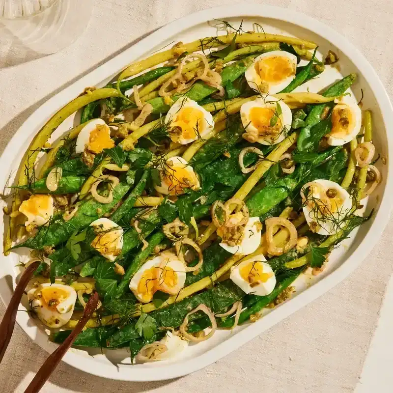 Mixed snap beans, eggs, and fresh herbs on a platter.