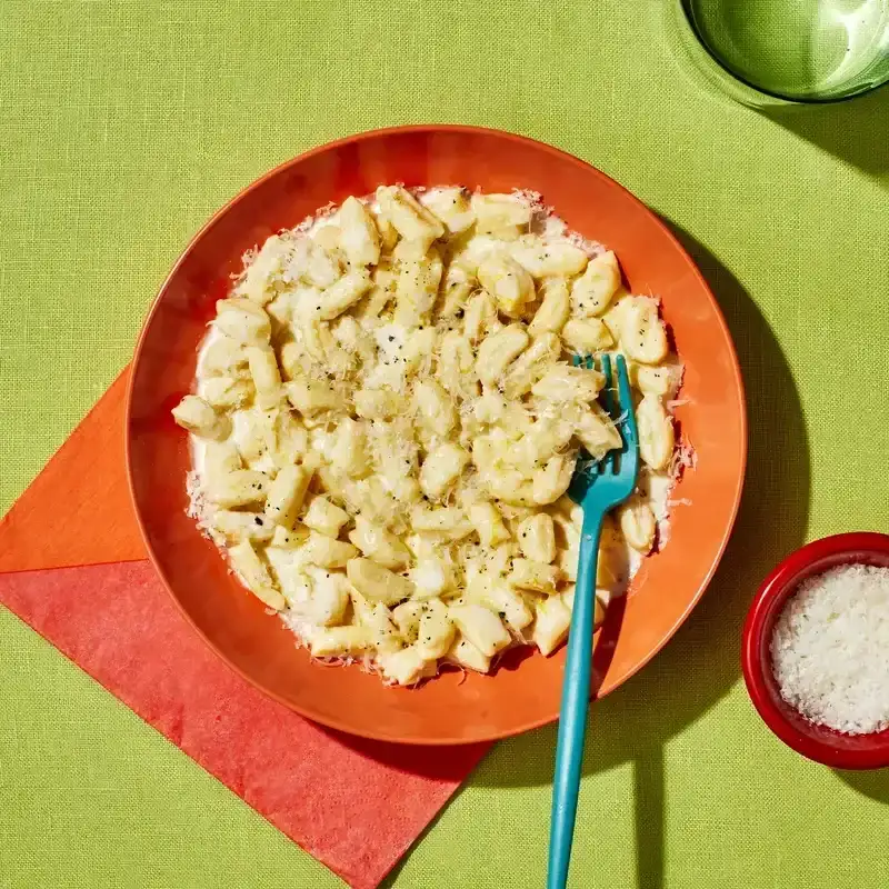 Ricotta Gnocchi plated in a orange bowl placed on a green surface