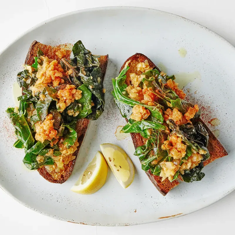 Lentil-smothered greens on toast served with lemon wedges