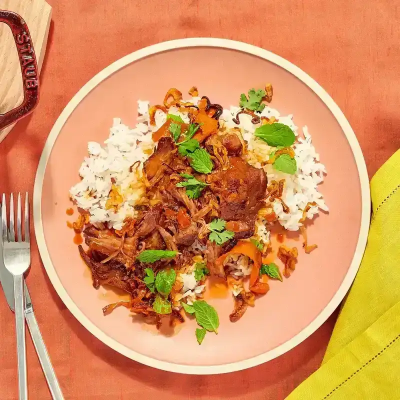 Citrus-Braised Pork With Crispy Shallots in a shallow bowl over rice