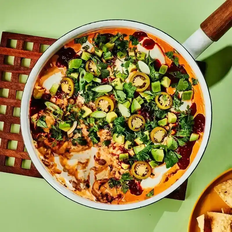 Warm Seven-Layer Skillet Dip on a trivet served with chips 