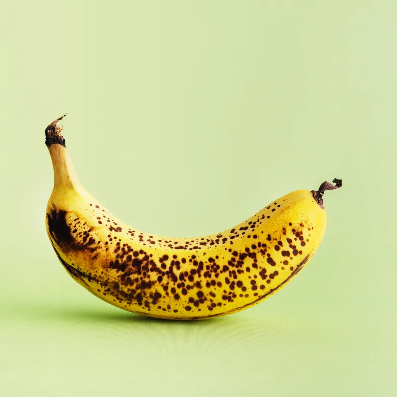 Overripe banana on a green background