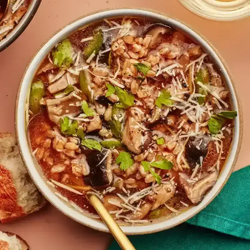 A brothy, hearty soup recipe packed with grains and big mushroom chunks, topped with chopped parsley and shredded Parmesan.