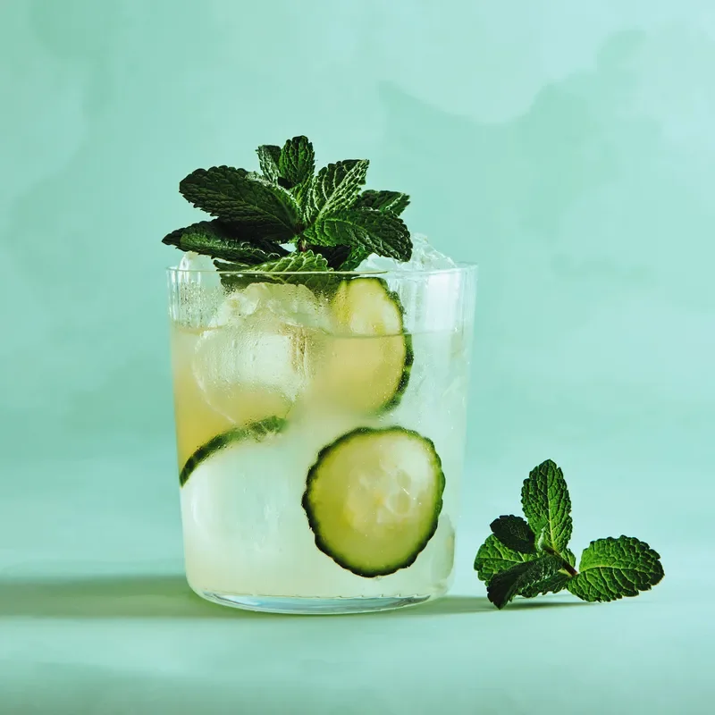 Cucumber lime drink in a glass garnished with mint.