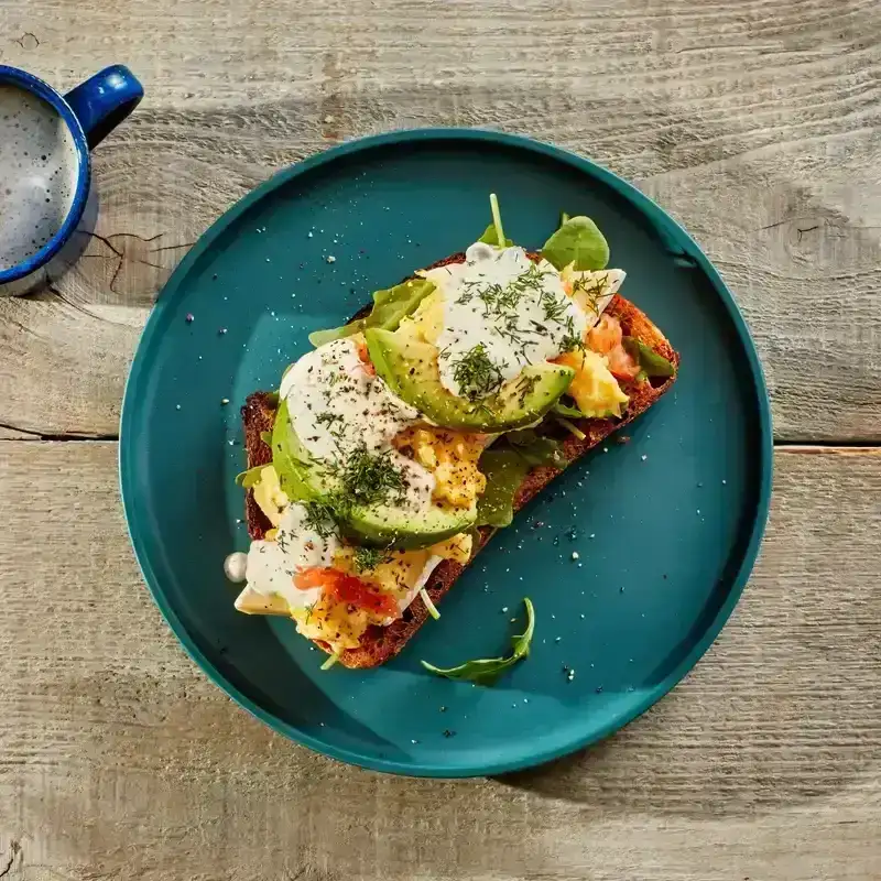 Hot-Smoked Salmon Scramble With Dill Cream on a blue plate placed on a wood table