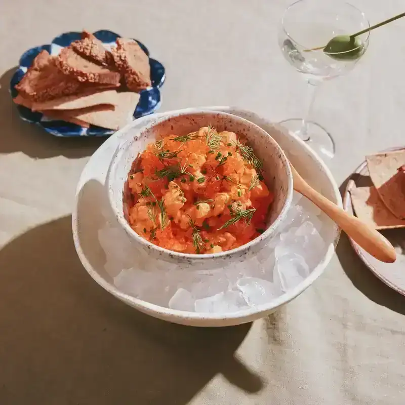 A bowl of salmon tartare sits atop a mound of ice, in a larger bowl.