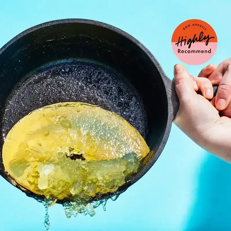 Cast iron pan being emptied of solid gelatinous residue. 