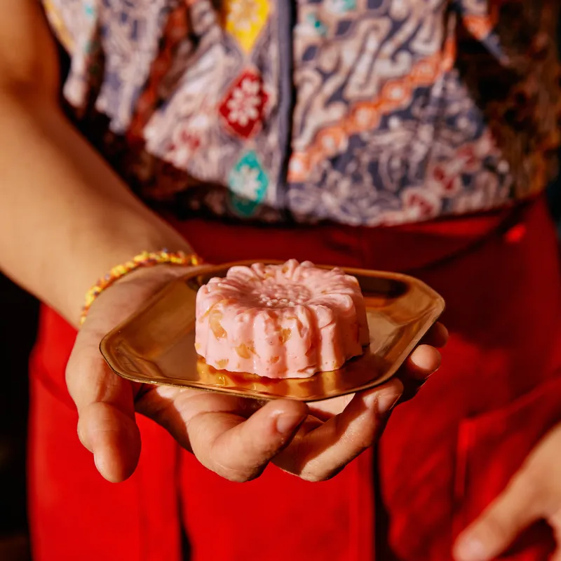 A woman holding one of Pasar's desserts on a gold dish.