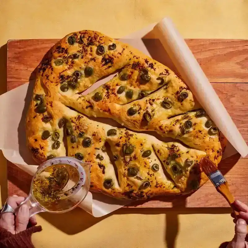 Fougasse with oil being poured onto it 