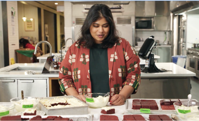 video stillshot of a chef preparing a meal behind a marble kitchen table.