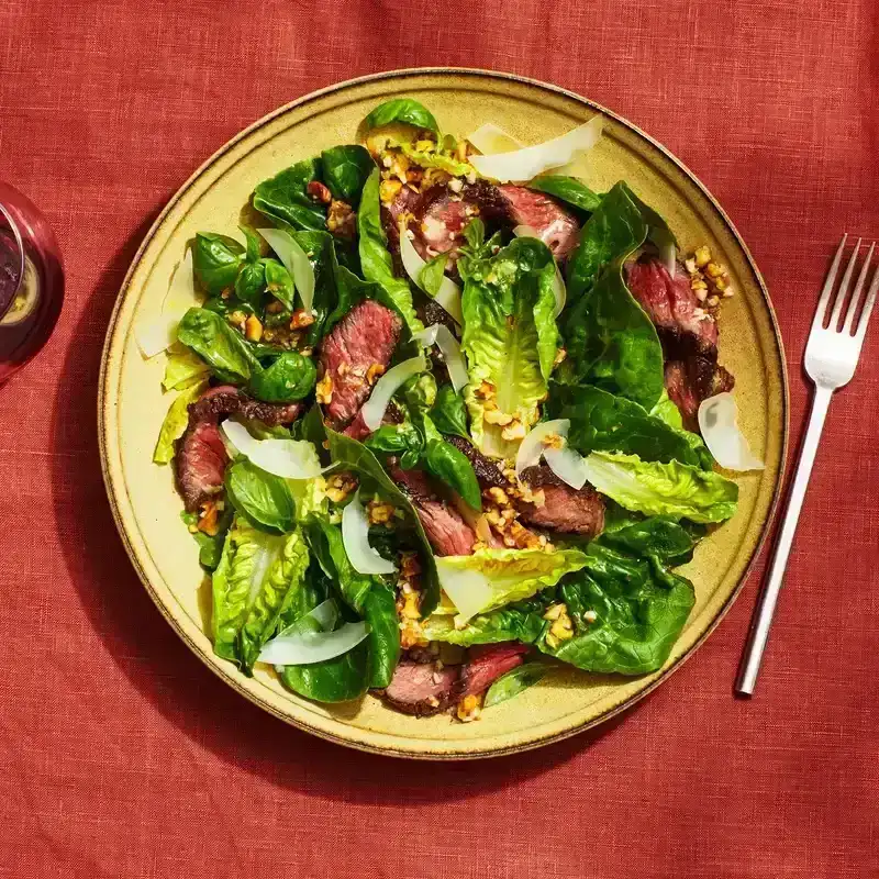 Pesto steak salad on a red tablecloth. 