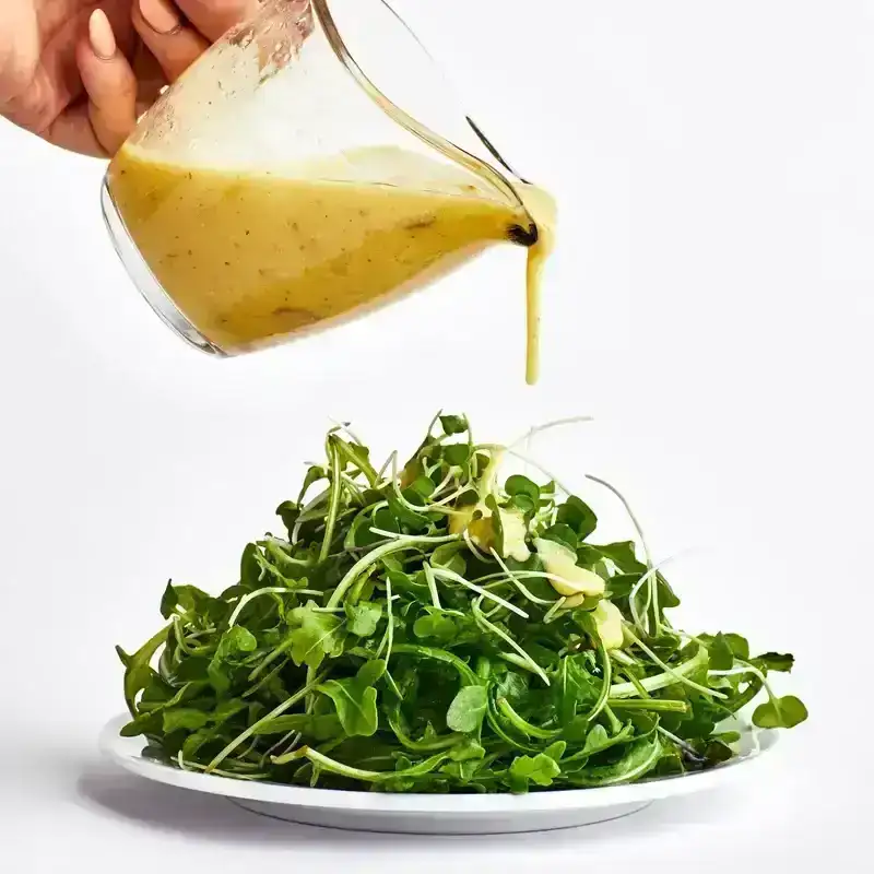 lemon vinaigrette being poured onto a salad