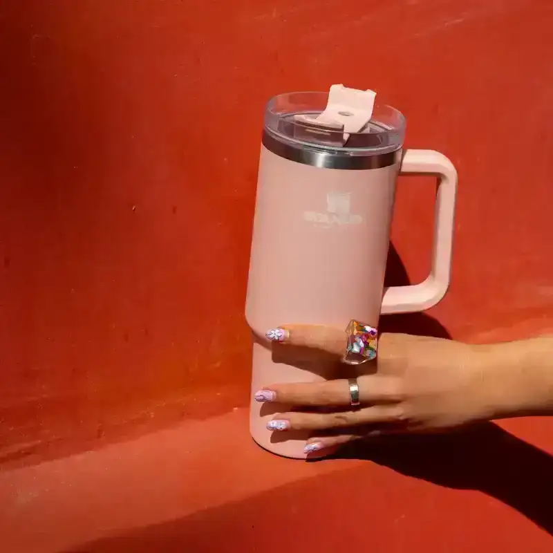 The Pink Adventure Quencher Travel Tumbler on a red wall, from Stanley, May 12, 2022. 