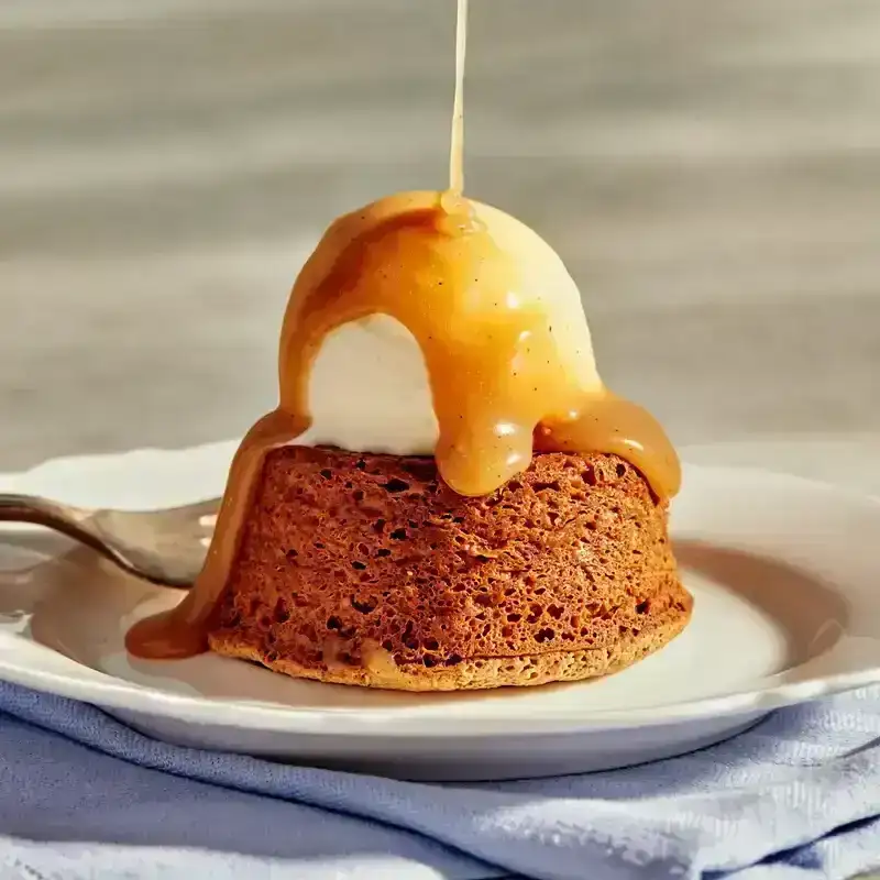 Walnut-Buckwheat Toffee Cake on a white plate with caramel being drizzled