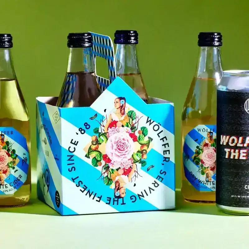 Row of different hard cider brands on a green surface