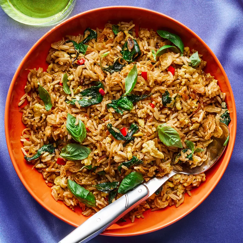 A bowl of basil fried rice with a spoon.