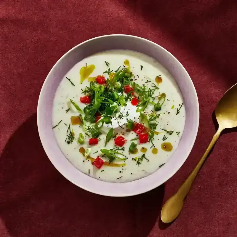 A bowl of potato soup topped with sliced scallions and dill