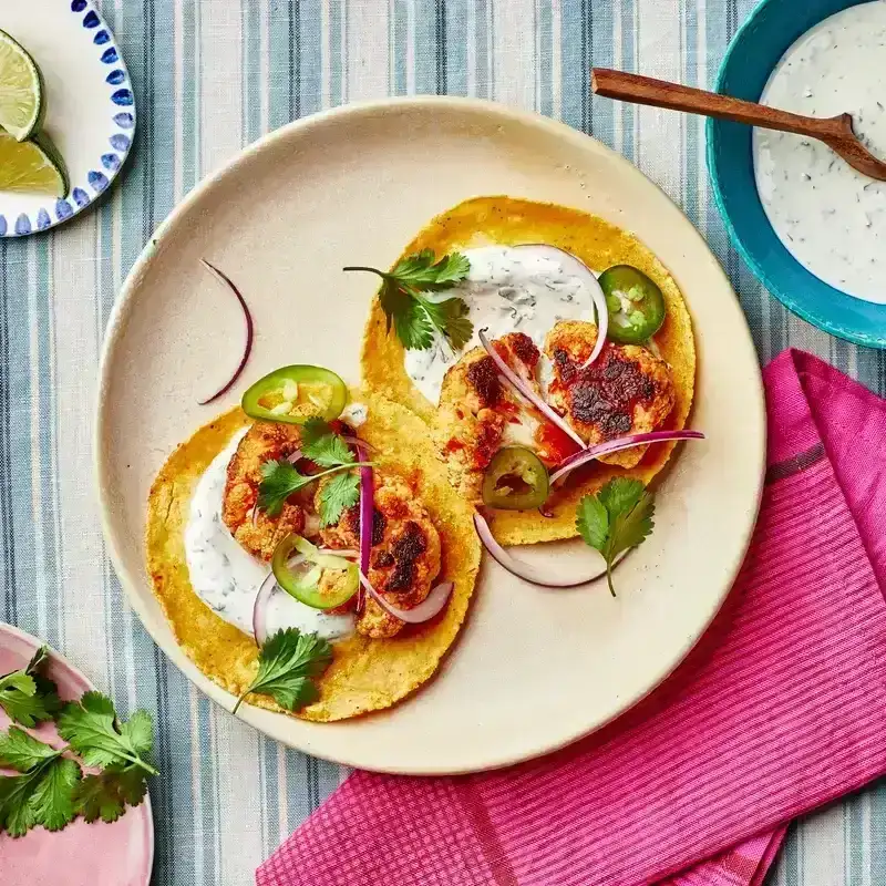 Two Chipotle-Roasted Cauliflower Tacos on a plate served with toppings