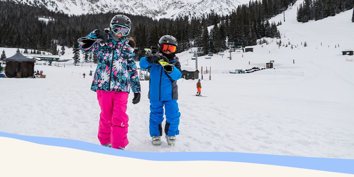 Two people on a ski mountain pointing off in the distance