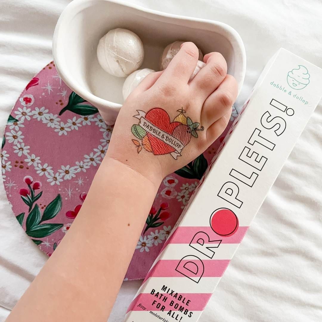 Child's hand with heart tattoo and playing with all-natural bath bombs