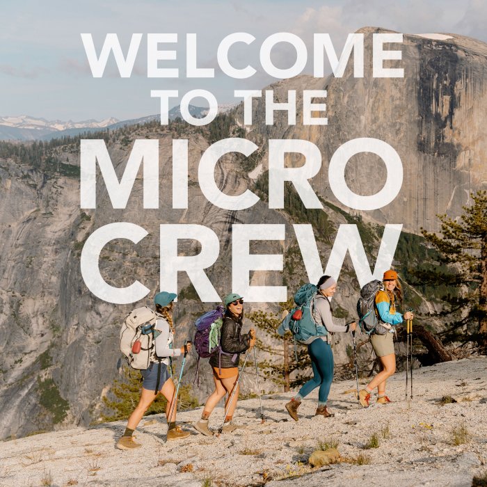 Check out the Micro Crew - four hikers walk up a rocky trail with a view of mountains behind them