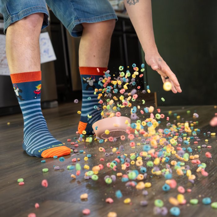 Shop Gifts for Dad - a bowl of cereal spills on the floor in front of feet wearing blue and orange striped socks