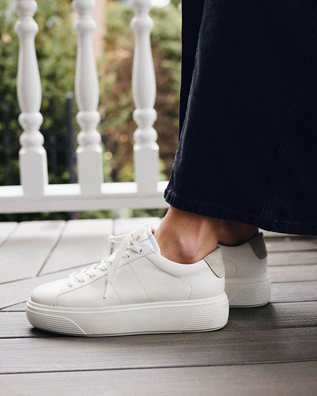 Model standing on porch wearing white sneakers