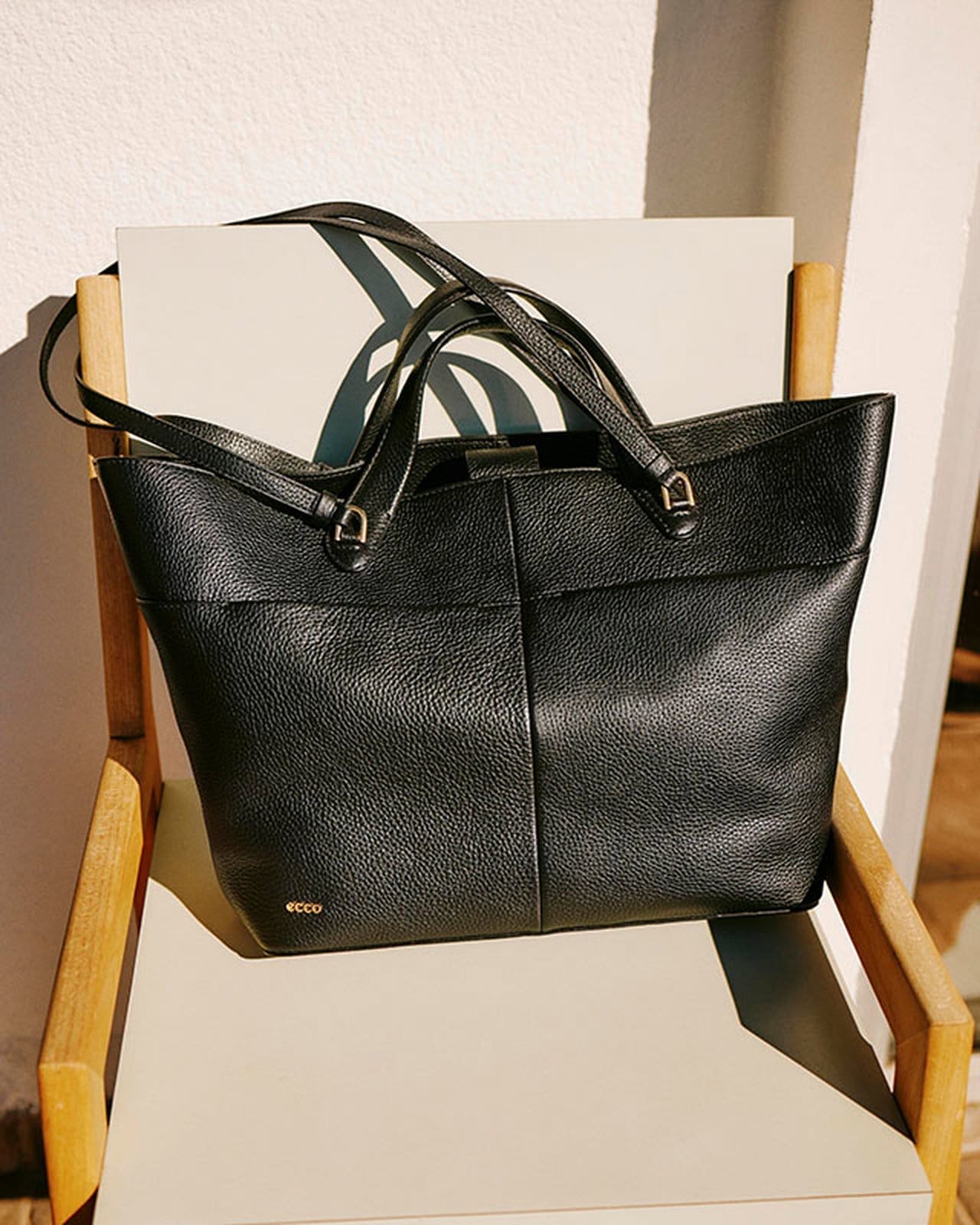 Black leather bag on tan chair