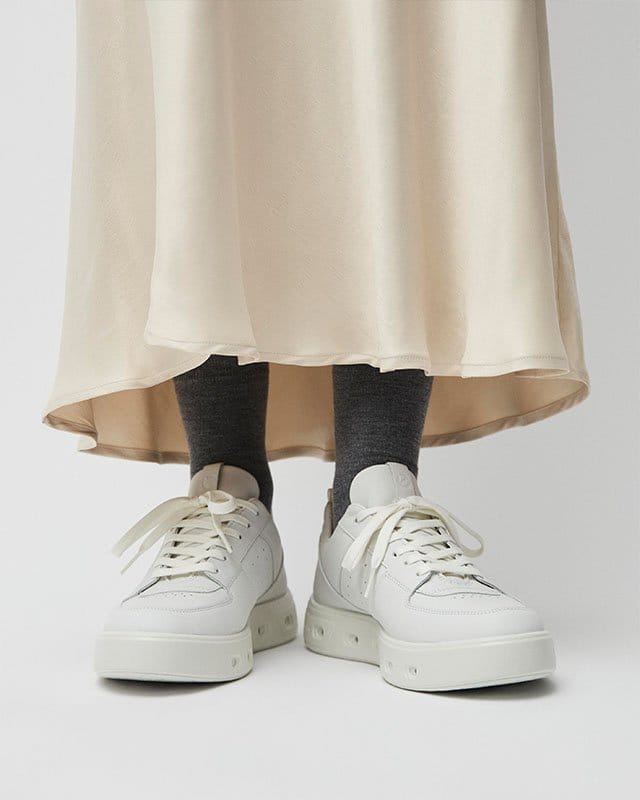 Woman wearing skirt and white sneakers